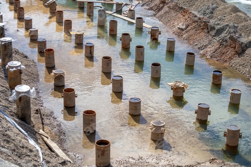 Preview: Row Of Construction Piers On The River Bank. Steel Pillars For Construction.