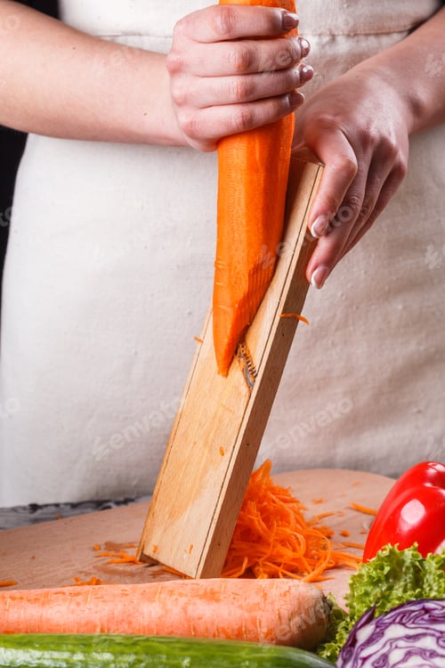 Preview: Young Woman In A Gray Apron Cuts Carrots