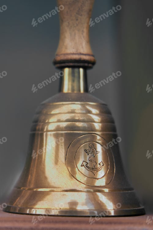Preview: Old Ship Hand Bell Made Of Yellow Metal With An Anchor Pattern, Close-Up