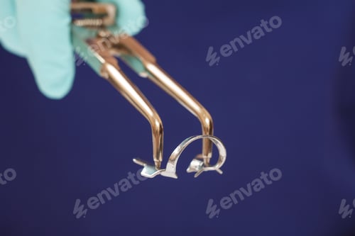 Preview: Close-Up View Of Dentist'S Hand In A Latex Glove With Dental Tongs And Clasp. Shallow Depth Of