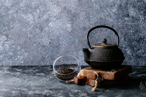 Preview: A Black Metal Teapot And A Black Tea Over Dark Texture Background