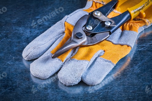 Preview: Safety Gloves With Tin Snips On Scratched Vintage Metallic Background Construction Concept.