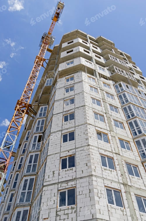 Preview: Building Crane And Building Under Construction Against Evening Blue Sky