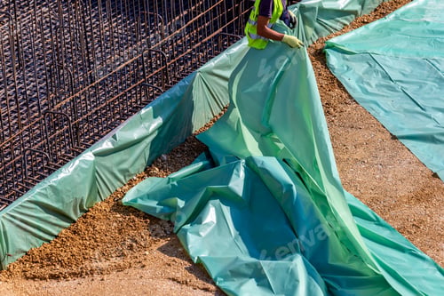 Preview: Worker Installing Plastic Membrane Before Pouring Concrete Slab, Helping To Prevent Moisture From