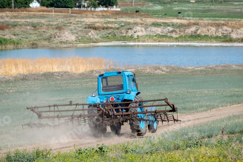 Preview: Old Tractor With Harrow Is Driving Along The Country Road