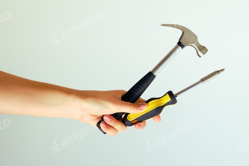 Preview: Construction Tools On Outstretched Arms. Hammer And Screwdriver In Hand On A White Background