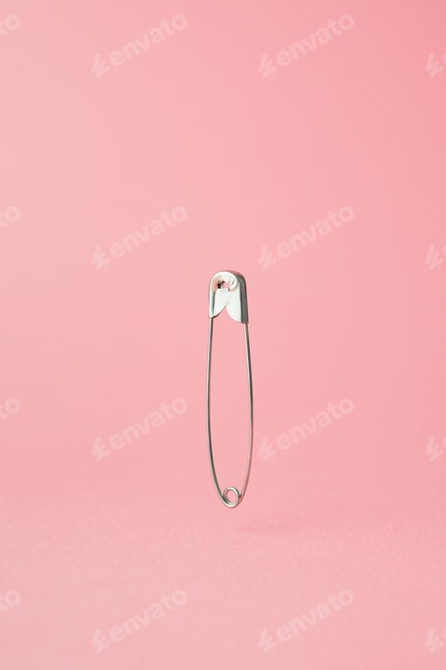 Preview: Safety Pin In The Air Over Pink Background
