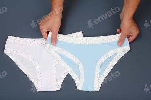 Preview: Women'S Hands Holding Beautiful Cotton Panties On Gray Background. Woman Underwear Set. Top View.