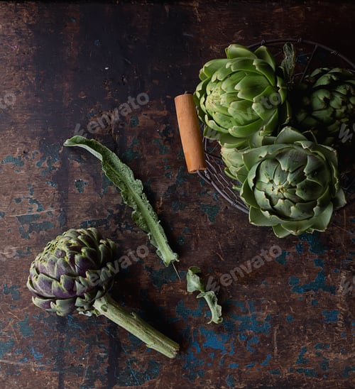 Preview: Fresh Organic Artichokes In A Metal Basket Over A Rustic Wooden Background. Top View