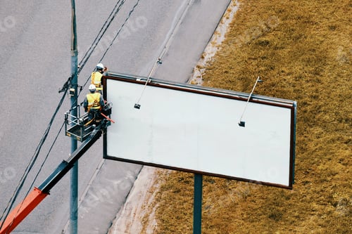 Preview: Workers Hang A Roadside Poster On A Billboard Near A Road