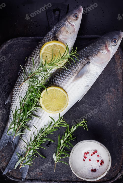 Preview: Fresh Mullet On A Marble Board Over Stone Vintage Black Background With Rosemary And Lemon Seasoned