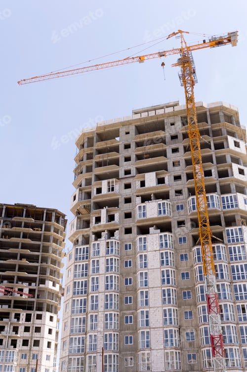 Preview: Building Crane And Building Under Construction Against Evening Blue Sky