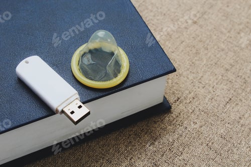 Preview: Unpacked Condom, Flash Drive And Book On The Background Of The Bed, Toned