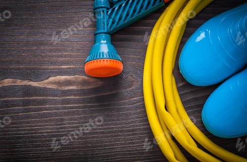 Preview: Twisted Rubber Hose With Spray Nozzle And Gumboots On Vintage Wooden Board Gardening Concept.