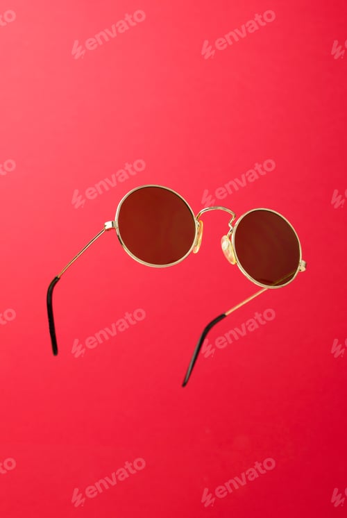 Preview: Round Sunglasses In The Air Over Red Background