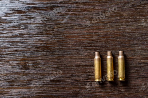 Preview: Empty Bullet Casings On A Dark, Wooden Table.