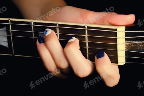 Preview: Female Hand With Manicure Lying On The Wooden Neck Of The Guitar. Woman Guitarist Clamped A Chord