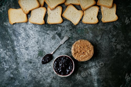 Preview: Bowls Of Raspberry Jelly And Peanut Butter With Slices Of Toasted Bread On The Rustic Metal