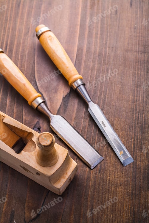 Preview: Two Carpentry Chisel And Old Fashioned Woodworkers Plane On Vintage Wooden Board