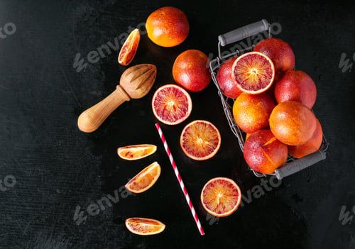 Preview: Sicilian Half Blood Oranges Squeezed And Cut Into Piecies Over Black Wooden Background. Top View