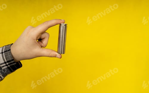Preview: Battery In Hand Close Up On A Yellow Background