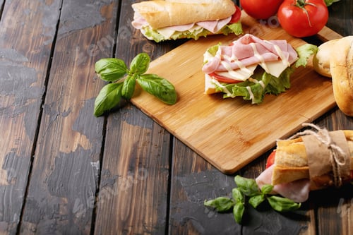 Preview: Homemade Sandwich: Tomatoes, Cheese, Ham, Lettuce And French Baguette On Wooden Cutting Board Over