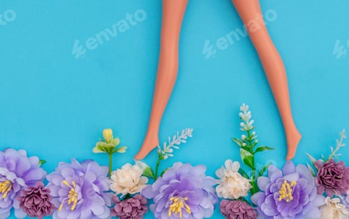 Preview: Creative Floral Concept With Doll Legs And Flowers On Pastel Blue Background. Flat Lay Design
