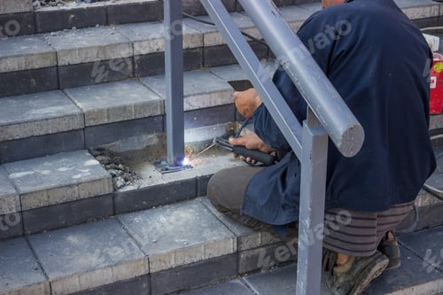 Preview: Tradesman Welding Metal Railing on Stone Steps