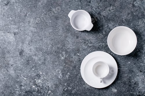 Preview: Variety Of Empty White Ceramic Plates And Bowls Over Dark Texture Background. Top View, Flat Lay