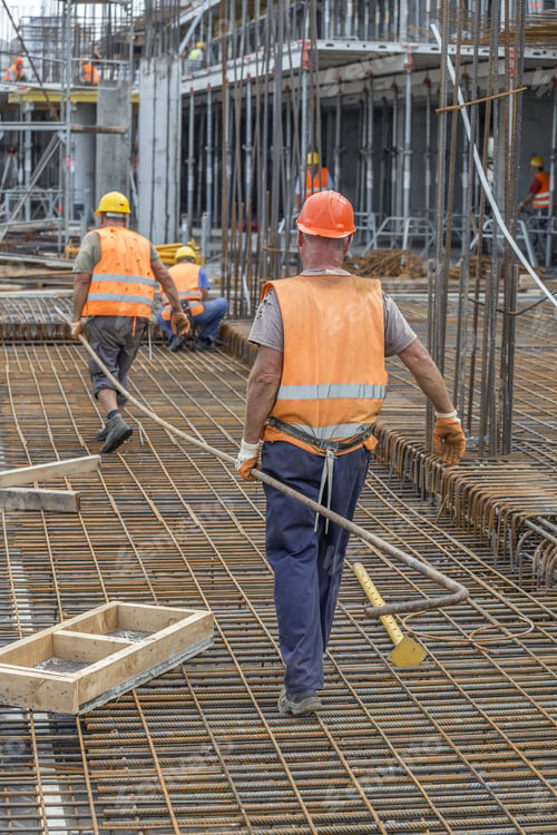 Preview: Construction Workers Carrying Heavy Steel Bar At Construction Site. Selective Focus.