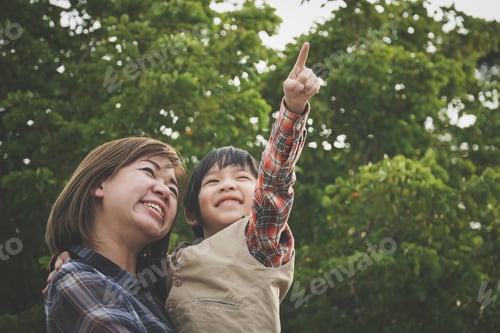 Preview: Asianmother And Her Son Looking Up And Pointing Outdoors