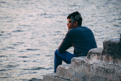 Preview: Young Indian Male Model In Glasses Sitting On Stairs Besides Lake At Wankaner, Gujarat, India