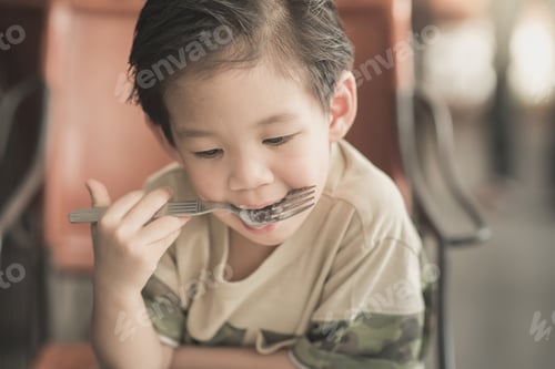 Visualização: Linda criança asiática comendo espaguete à carbonara no restaurante, filtro vintage