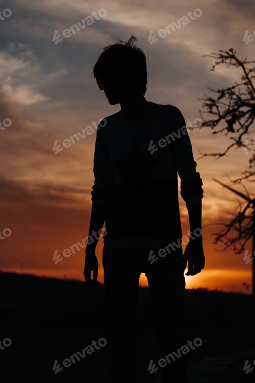 Preview: Silhouette Of A Man Standing In Front Of Trees And Windmill During Sunset
