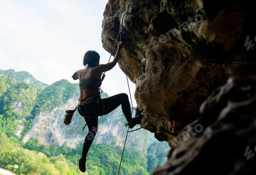 Preview: Confidence Asian Woman Climber With Safety Rope Climbing High Up On Rocky Mountain At Tropical