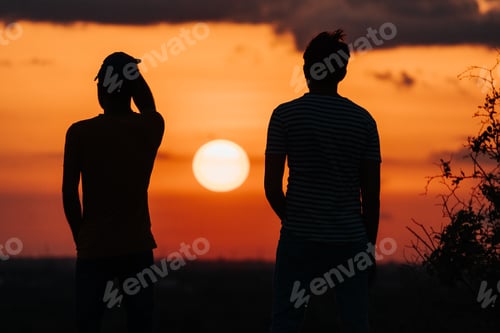 Preview: Silhouette Of Two Indian Male Friends Standing In Front Of The Sun During The Sunset