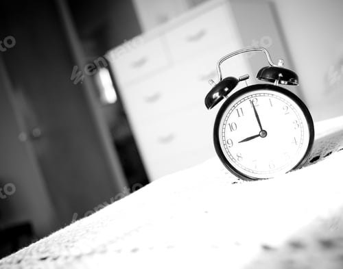 Preview: A Black Alarm Clock On A White Tablecloth.