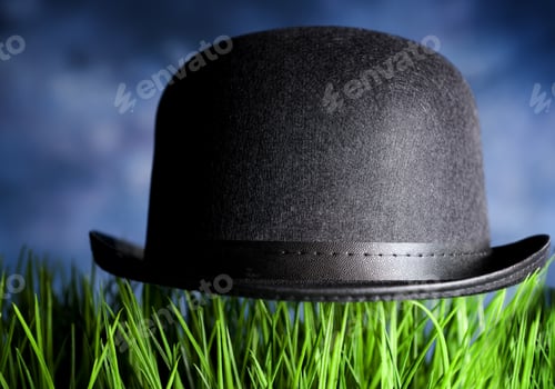 Preview: A Black Bowler Hat Placed On Top Of Lush Green Grass Blades.