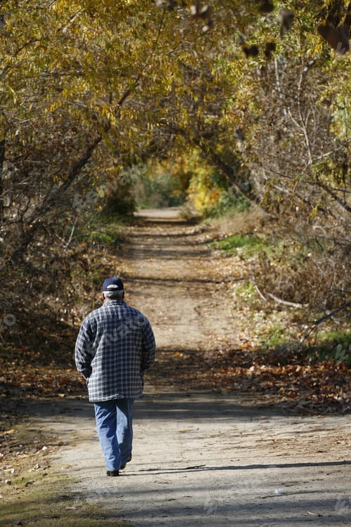 Preview: Man Walking Down A Dirt Path Surrounded By Fall Color