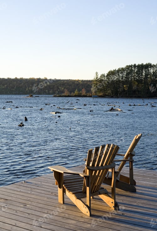 Preview: Two Chairs On A Dock Overlooking A Lake.