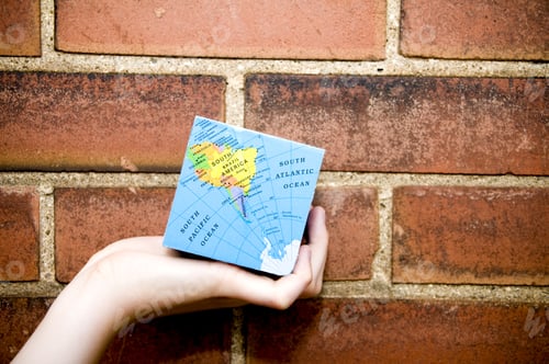 Preview: A Square Map Of The World Being Held In Front Of A Brick Wall.