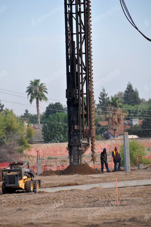 Preview: A Power Auger To Drill Deep Holes Is Supported By A Crane On A Construction Job Site