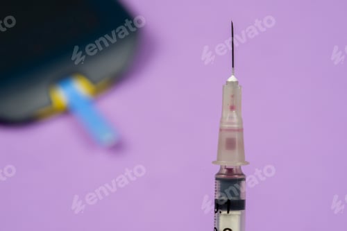 Preview: Insulin Syringe In The Foreground, With Blurred Diabetes Glucometer In The Background