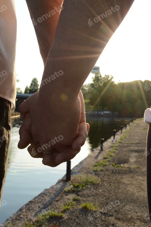 Preview: An Adult Couple Hold Hands During A Romantic Sunet Walk Along The Waters Edge.