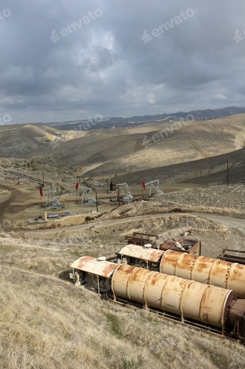Preview: Old Oil Field Heaters Are In The Foreground While Downhill A Group Of Oil Wells Are Located In The