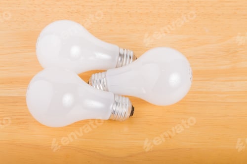 Preview: Three Incandescent Lightbulbs On A Wood Table