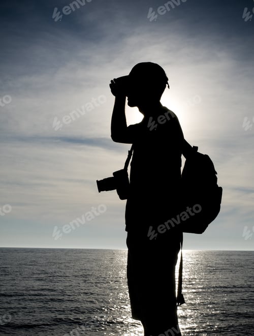 Preview: The Figure Of A Photographer Silhouetted Against The Darkening Sky.