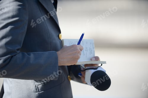 Preview: Reporter Writing His Notes In A Notebook And Holding The Microphone