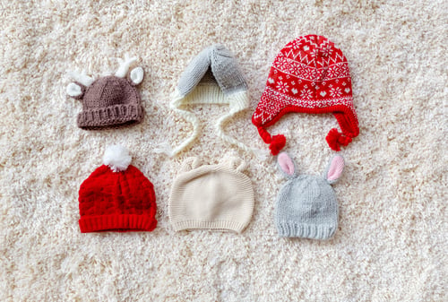 Preview: Assorted Winter Style Knitted Hats On A White Carpet