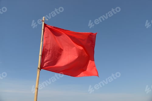 Preview: Red Flag Swaying In The Wind On A Blue Sky Background.